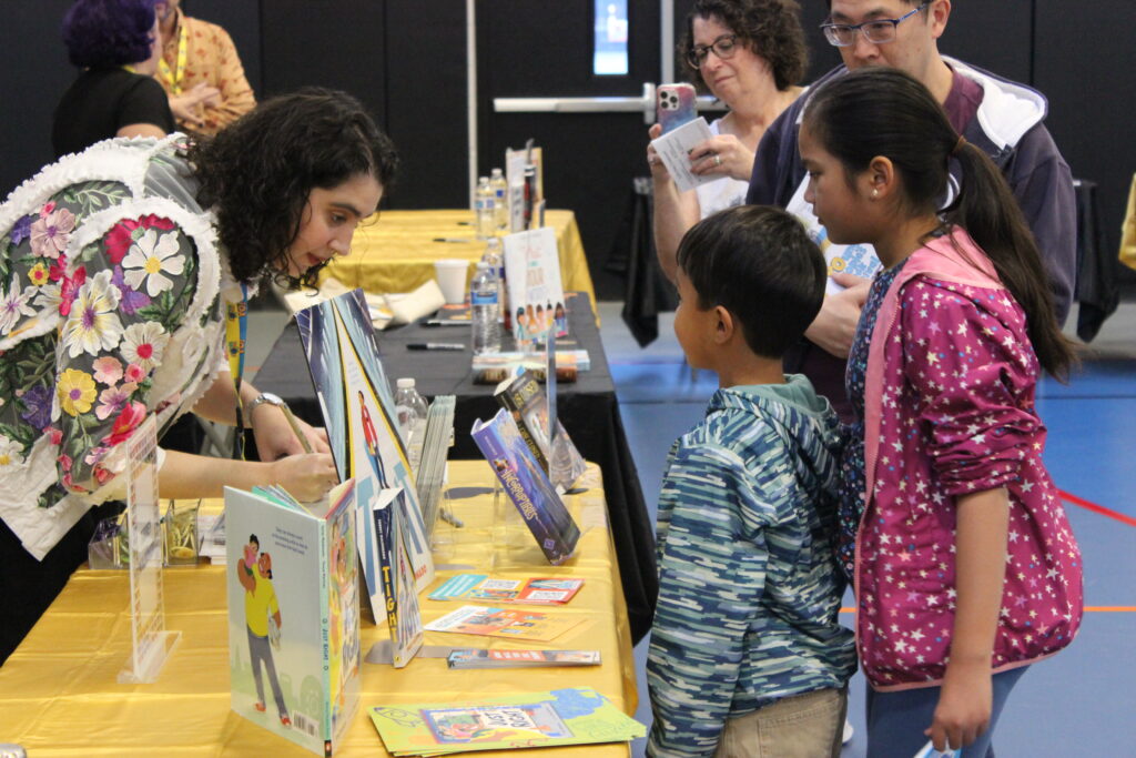 Lauren Magaziner signing books for a pair of young siblings.
