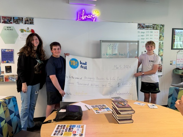 Heather Hebert of Children's Book World receiving a large check from YO Book Fest for the Bringing Books to Life nonprofit organization.